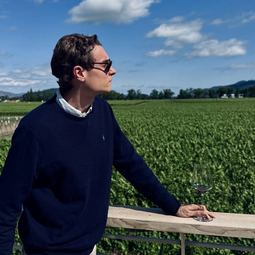 The candidate surveying a Napa vineyard with a glass of red wine